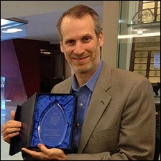 rater8 CEO Evan Steele poses with an award for his first company, SRS