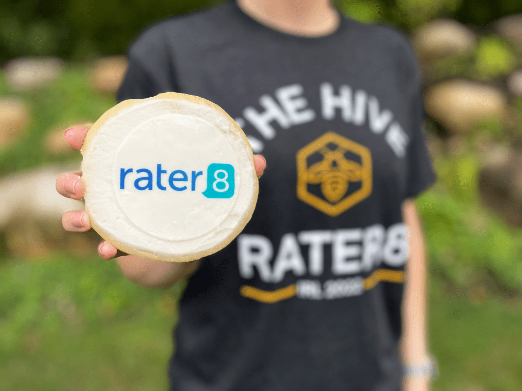 A rater8 employee holds a cookie with the rater8 logo on it; IRL 2022